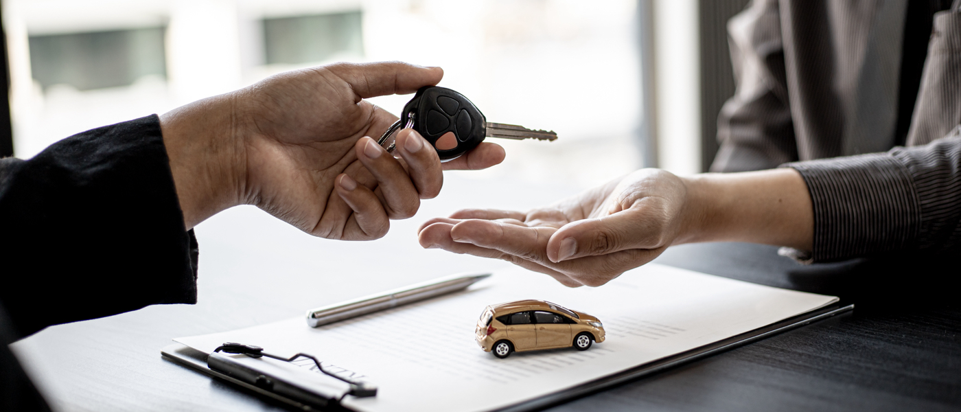 Übergabe eines Autoschlüssels über einem Vertrag mit Modellauto